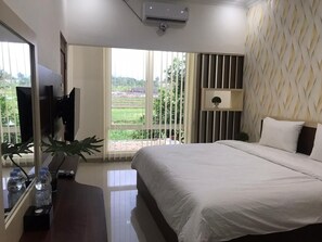 Un dormitorio con una cama grande, televisión, planta y vistas al exterior.