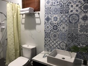 A bathroom with a toilet, sink, and shower curtain. - Reddoorz Syariah @ Omah Sawah (Ngaglik)