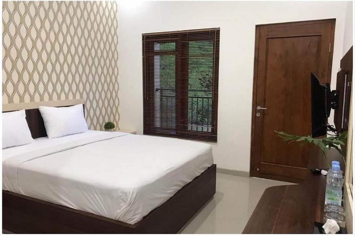 A bedroom with a bed, a wooden door, a window with blinds, and a wall with a geometric pattern.
