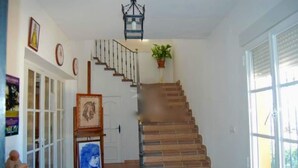 A staircase with a handrail, a potted plant, and framed artwork on the wall.