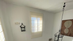 A staircase with a metal railing, a window with blinds, and a wall-mounted light fixture.