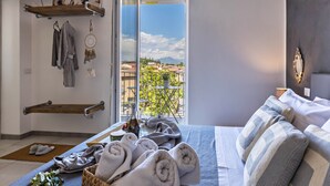 Un dormitorio con cama, toallas, ventana con vistas y una estantería con objetos.