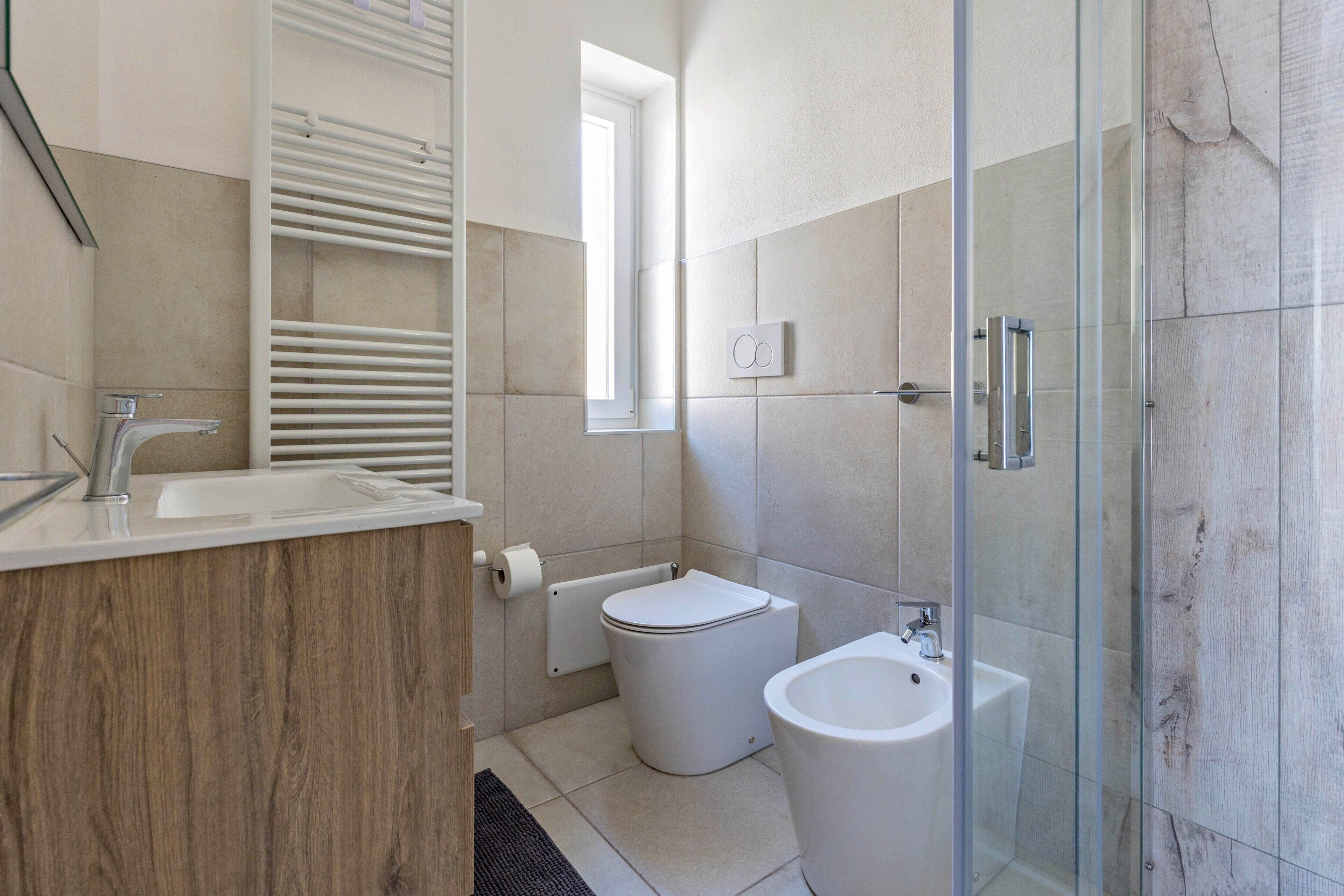A modern bathroom with a toilet, bidet, and glass-enclosed shower.