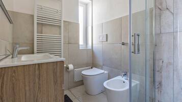 A modern bathroom with a toilet, bidet, and glass-enclosed shower.