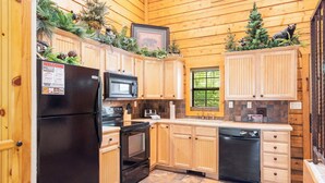 Una cocina estilo cabaña de madera con refrigerador, microondas, horno y lavavajillas.