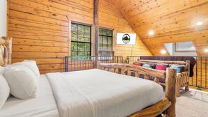 Una habitación de cabaña de madera con una cama, un ventanal y un balcón.