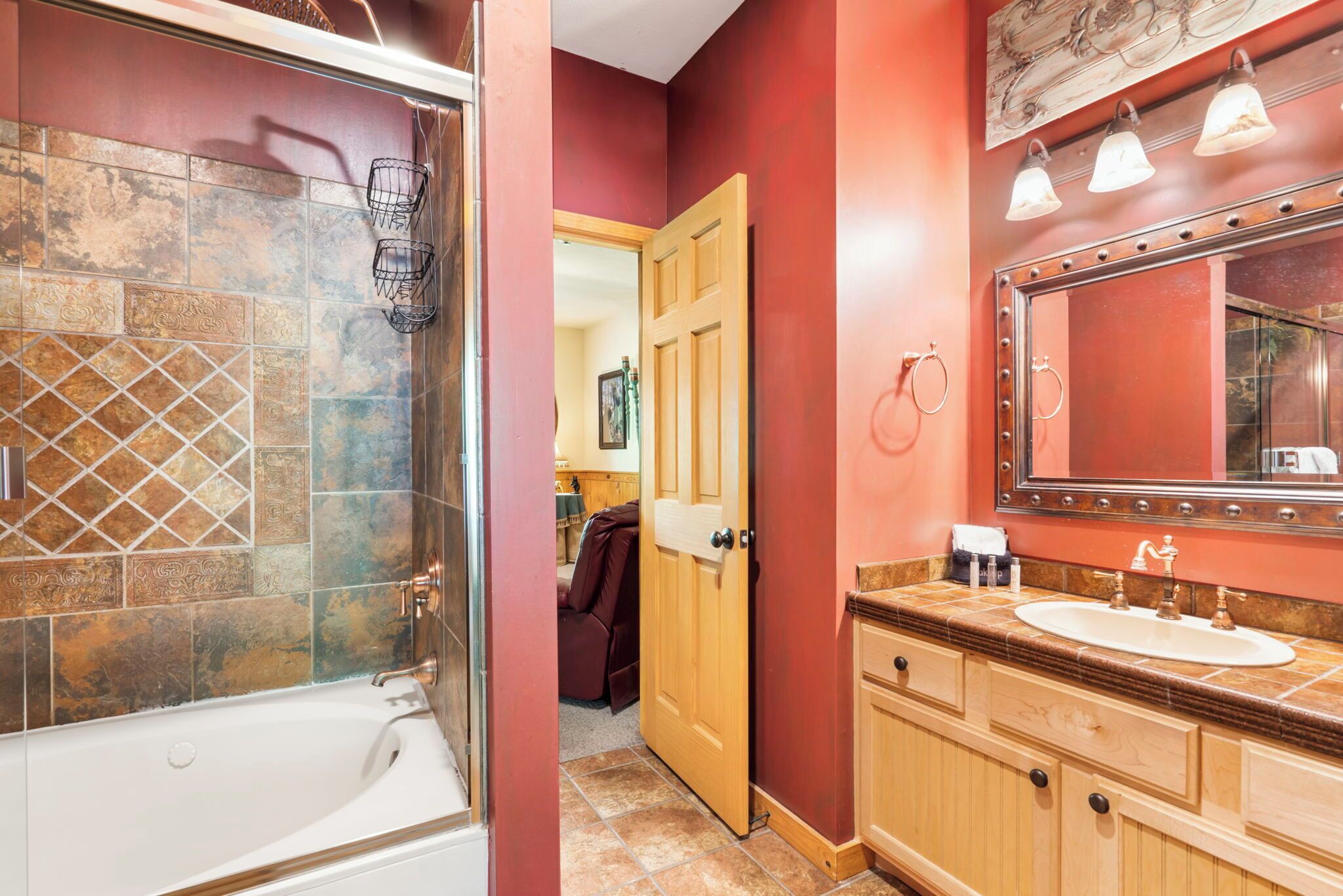 A bathroom with a bathtub, a vanity with a mirror, and a shower area.