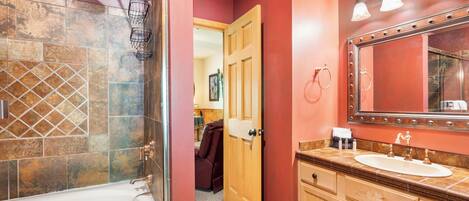 A bathroom with a bathtub, a vanity with a mirror, and a shower area.