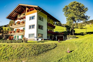 Um hotel com vários andares, varandas, um gramado bem cuidado e uma paisagem acidentada.
