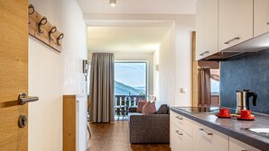 Eine moderne Küche mit Holztür, einer Couch und Blick auf einen Balkon.
