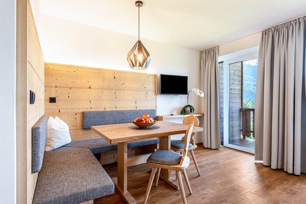 Une pièce moderne avec un mur en bois, une table à manger agrémentée d’un panier de fruits, un banc et un téléviseur fixé au mur.