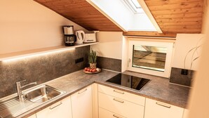 A kitchen with a built-in oven, a sink, and a window above the countertop.
