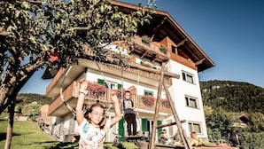 Un edificio de dos pisos con balcones, una escalera de madera y un patio cubierto de césped.