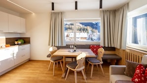 Una cocina moderna con armarios blancos, una mesa de comedor de madera y vistas a un paisaje nevado.