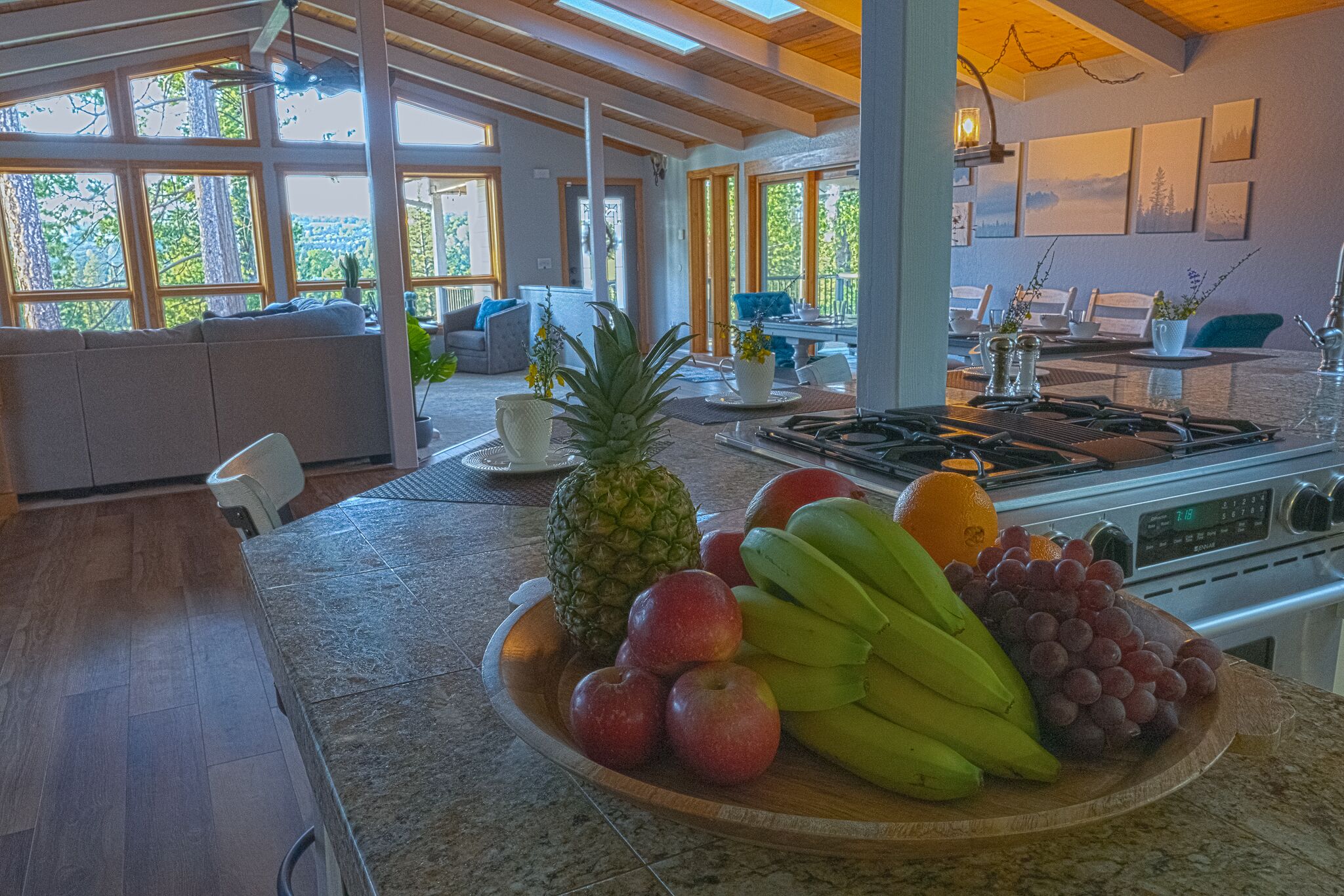 Una cocina con un frutero que contiene manzanas, plátanos, uvas y una piña.