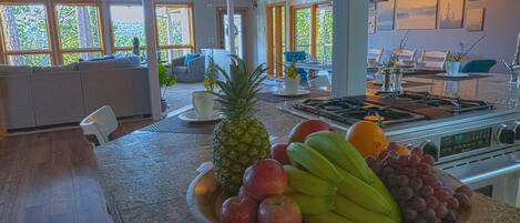 Una cocina con un frutero que contiene manzanas, plátanos, uvas y una piña.
