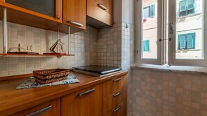 Una cocina con armarios de madera, salpicadero de azulejos, una ventana con contraventanas y una cesta en la encimera.