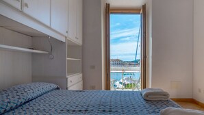 Un dormitorio con cama, armario y vistas a un puerto deportivo.