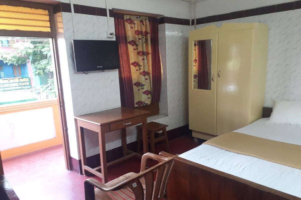 A room with a bed, a desk, a chair, a wardrobe, and a television on the wall.