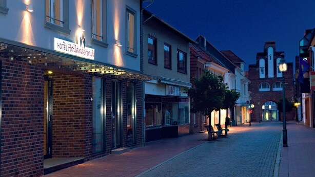A hotel named "HOTEL Hollanderstrasse" with a brick facade and illuminated signage.