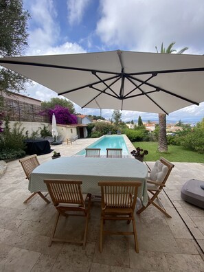 Eine Außenpatio mit Billardtisch, Stühlen und einem großen Sonnenschirm.