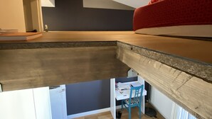 Une chambre située dans un espace de type « loft », avec un plafond en pente, un cadre de lit en bois et un coin bureau avec une chaise.