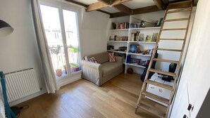 Une pièce avec un plancher en bois, un canapé, une bibliothèque et une échelle.