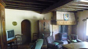 Un salón tradicional con chimenea, muebles de madera y televisor.