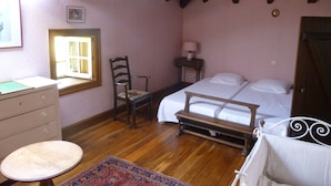 Un dormitorio con cama de madera, una silla, un escritorio y una ventana.