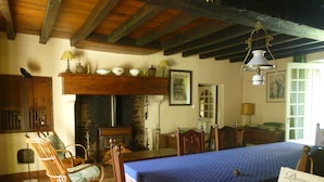 Comedor con una mesa de madera, sillas y mantel azul. Cuenta con chimenea, candelabro y un letrero de Duceat Chocolate.