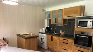 Eine kleine Küche mit Holzschränken, einer Waschmaschine, einer Mikrowelle und einem Backofen.