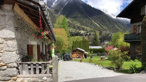 Ein Steinhaus mit einem hölzernen Balkon und hängenden Blumen.
