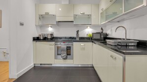 Una cocina moderna con gabinetes blancos, encimera negra y horno de acero inoxidable.