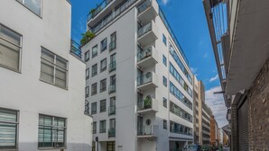 Un edificio residencial de varios pisos con balcones, garaje y vista a la calle.
