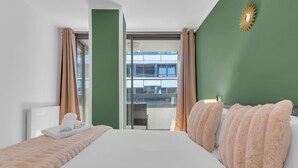 Habitación de hotel con una cama grande, paredes verdes y vista a la ciudad por la ventana.