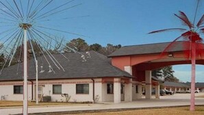 A building with a simple, functional design, featuring a flat roof and a single-story structure. - Scottish Inn & Suites IAH West (Houston)