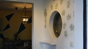 A room with a round mirror, geometric wall pattern, and a hanging light fixture. - 2 Zimmer FeWo mit Außenpool und Sauna (Sulzfeld am Main)