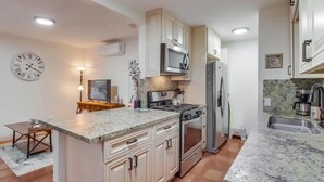 Une cuisine moderne avec des armoires blanches, un comptoir en granit, un four à micro-ondes, une cuisinière et un réfrigérateur.