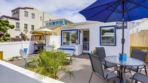 Une terrasse avec une table ronde, des chaises et un parasol bleu.