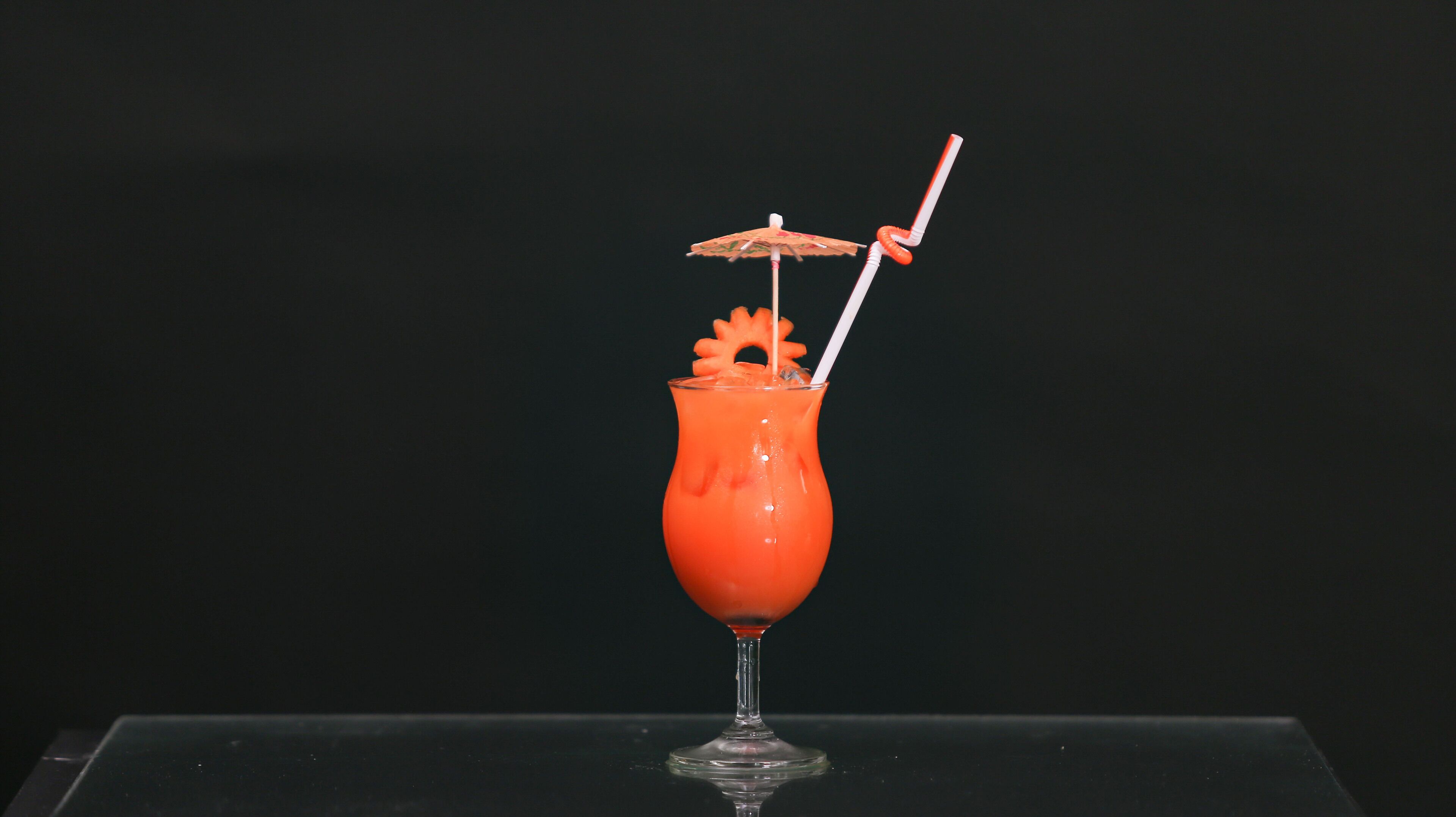 Un cocktail in un bicchiere alto, con una cannuccia e un ombrellino decorativo.