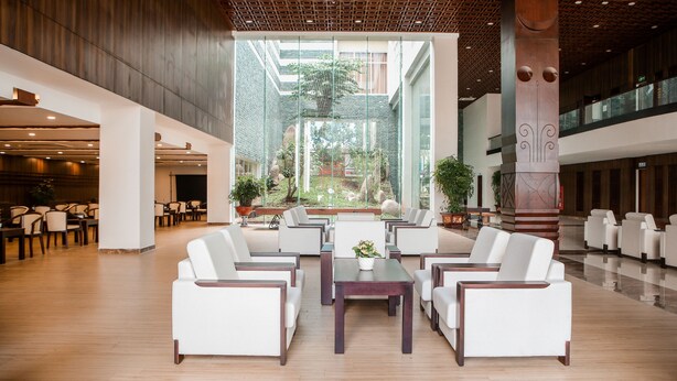 A spacious lobby with a high ceiling, modern furniture, and a view of a lush garden through large windows. - Elephants Hotel Buon Ma Thuot (Buon Ma Thuot)