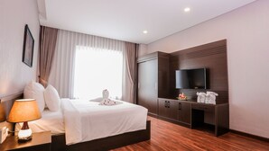 A hotel room with a bed, a TV, a desk with a lamp, and a wardrobe. - Elephants Hotel Buon Ma Thuot (Buon Ma Thuot)