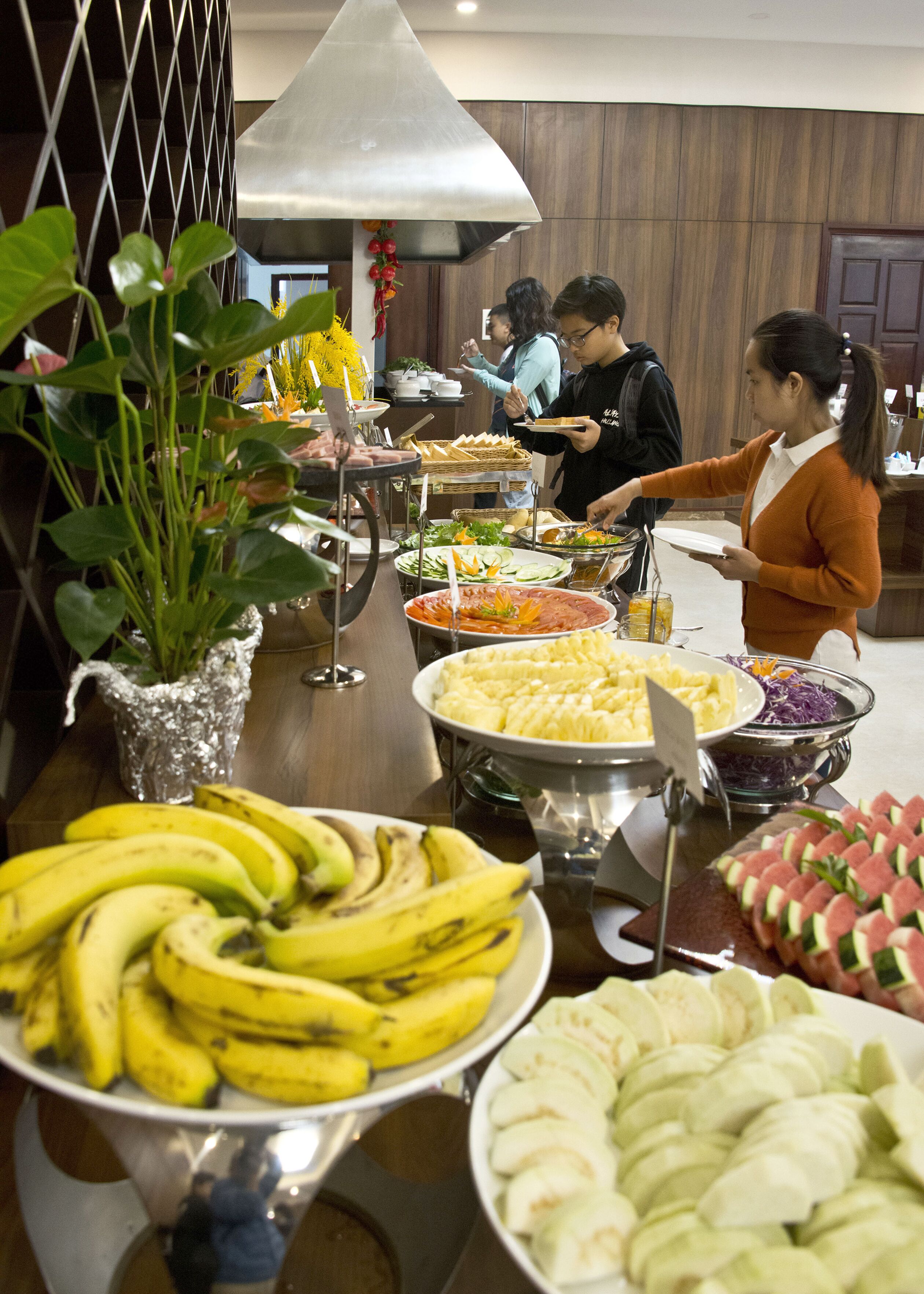 Un bufé con diversos alimentos, incluyendo plátanos, manzanas y ensaladas.