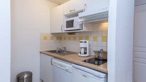 Une cuisine compacte équipée d’un four à micro-ondes, d’une machine à café et d’un lave-vaisselle.