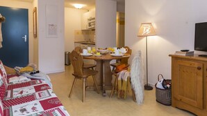 Un salon confortable avec un coin repas, un téléviseur et une lampe.