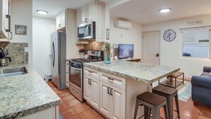 Een moderne keuken met granieten aanrecht, roestvrijstalen apparatuur en een centraal eiland met krukken.