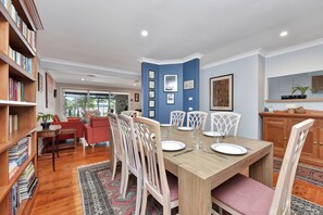 A dining area with a wooden table, white chairs, and a blue accent wall.