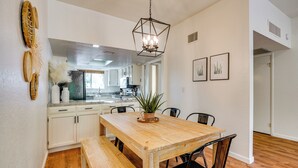 A dining area with a wooden table and bench, white cabinets, and a hanging light fixture. - Tucson Foothills Oasis Near Hiking Trails! (Tucson)