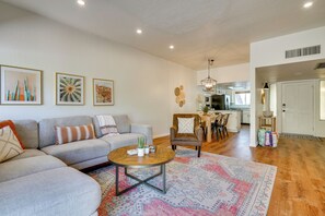 A living room with a sofa, armchair, coffee table, and artwork on the wall. - Tucson Foothills Oasis Near Hiking Trails! (Tucson)