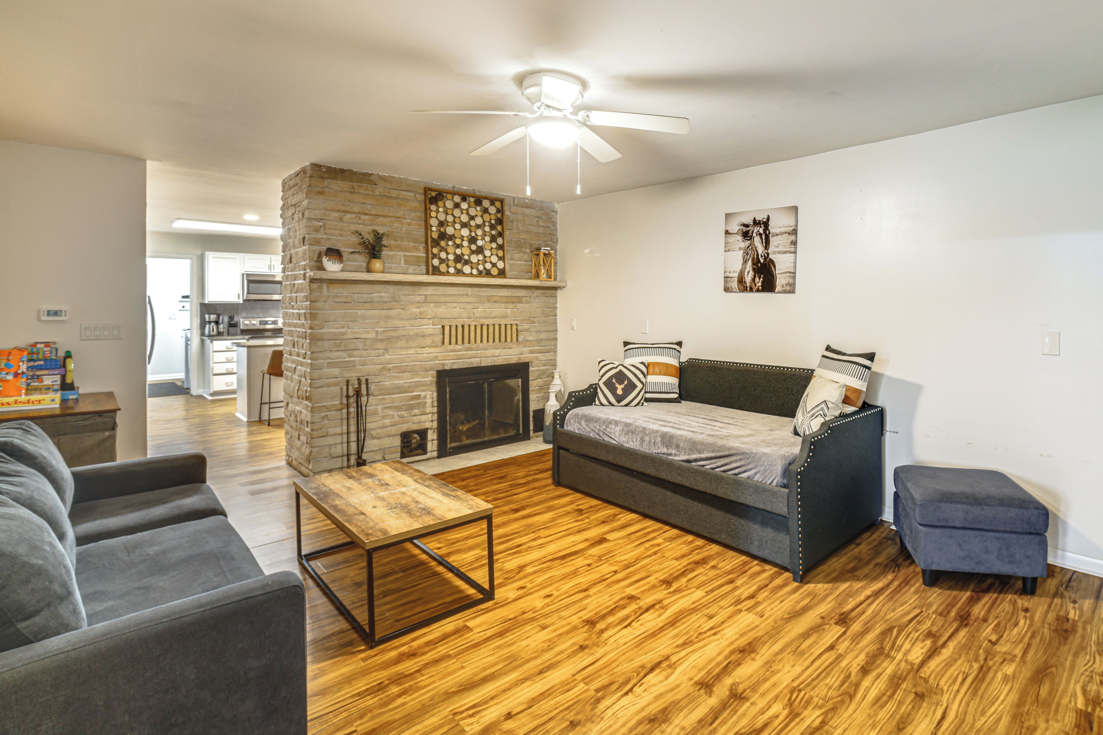 Un salon moderne avec une cheminée, un canapé, une table basse et un ventilateur de plafond.